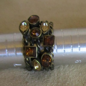 May include: A gold-toned ring with multiple bands adorned with amber and clear faceted stones.