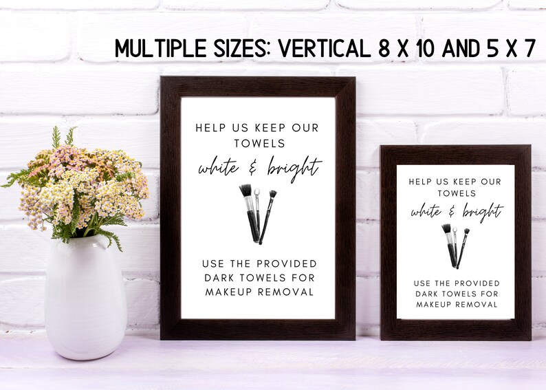 May include: Two framed signs with black frames and white backgrounds. The signs have black and white illustrations of makeup brushes and the text "Help us keep our towels white & bright. Use the provided dark towels for makeup removal."