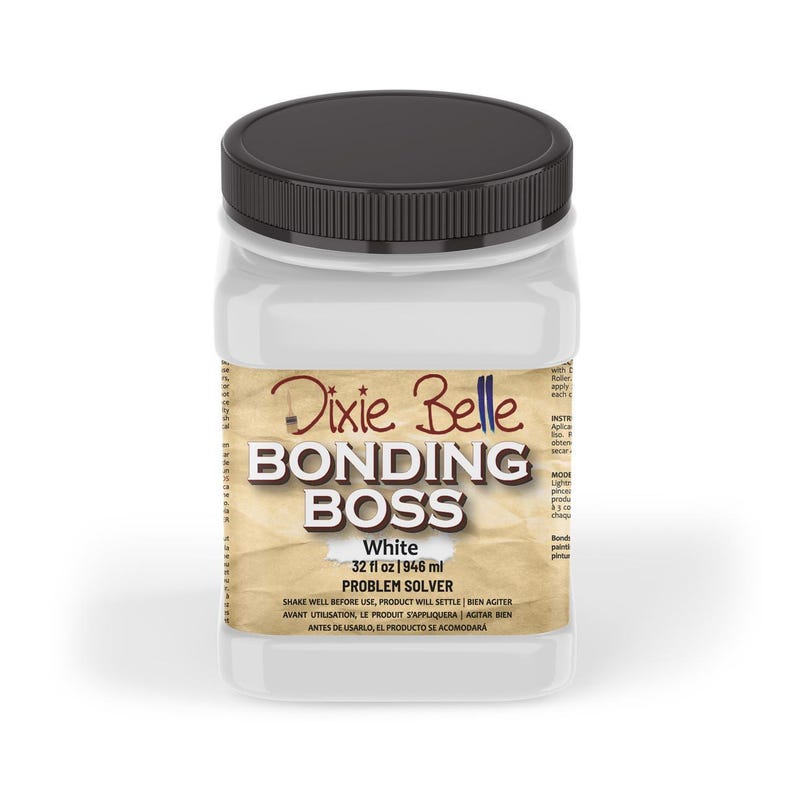 May include: A white plastic bottle with a black lid labelled "Dixie Belle Bonding Boss White 32 fl oz 1946 ml Problem Solver". The label has a brown, textured background and the text is in a black font.