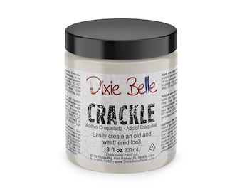 Puede incluir: Un tarro blanco con tapa negra etiquetado como "Dixie Belle Crackle" con el texto "Additivo Craquelado - Additif Craquelé" y "Easily create an old and weathered look". El tarro contiene 237 ml (8 fl oz) de medio craquelado.