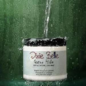 May include: A white jar of Dixie Belle Gator Hide with a black lid, featuring the text 16 fl oz | 473 ML | Stir Well, Repels water (not gators), and Protect your creation with nature's armor, while water pours over the top of the container.