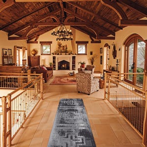 May include: A long, rectangular runner rug featuring a distressed, charcoal grey and light grey colour palette with a repeating geometric cross pattern. The rug is positioned centrally on a light-coloured stone floor in a large, open-plan room.