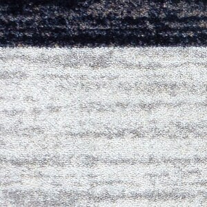 May include: A textile surface featuring a horizontal color-blocked design. The upper section consists of a dark, textured charcoal black band, while the lower, larger portion displays a light gray, mottled, and slightly heathered fabric texture.