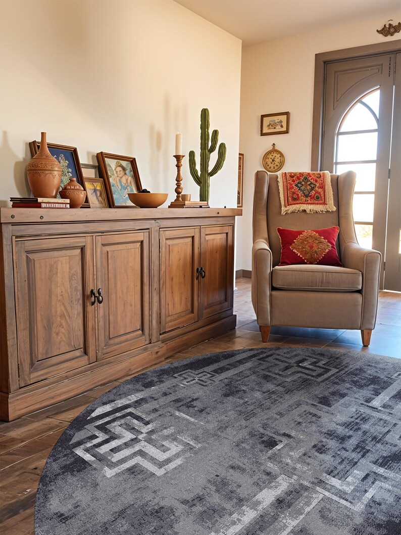 May include: A wooden sideboard with four doors and black hardware, topped with terracotta vessels, framed art, a candle, and a cactus. Beside it sits a beige wingback chair with a red patterned pillow and a small tapestry, atop a dark grey circular rug.