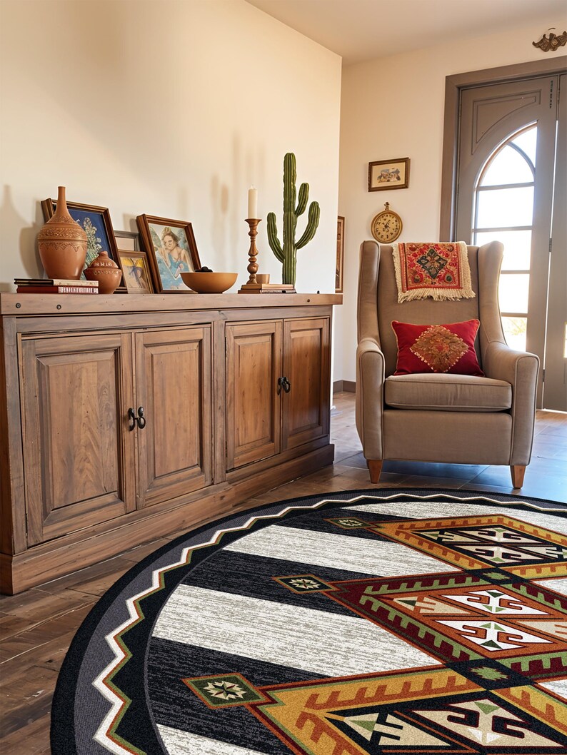 May include: A round area rug featuring a geometric pattern in black, white, rust orange, and olive green. The design includes a central diamond motif with intricate lines and angular shapes, surrounded by a wide black border with a white zigzag edge.