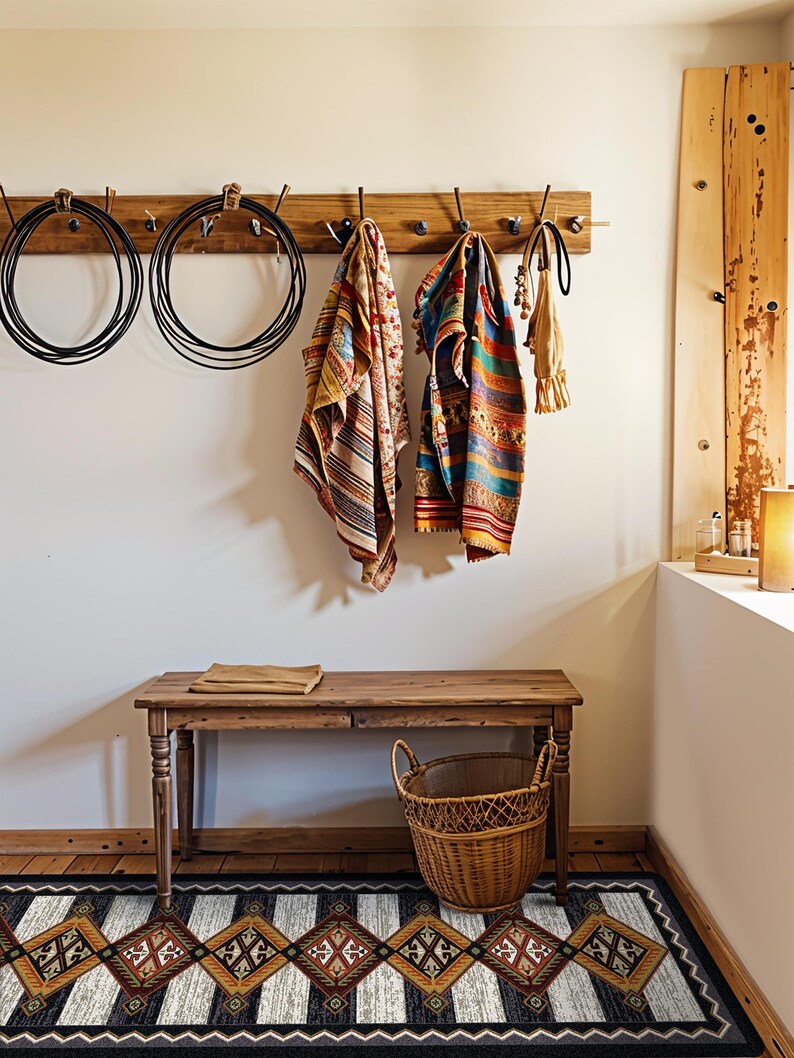 May include: A rectangular area rug featuring a repeating diamond pattern in shades of brown, black, and white with a geometric border. The rug is positioned on a wooden floor beneath a wooden bench, a wicker basket, and a wall-mounted coat rack.