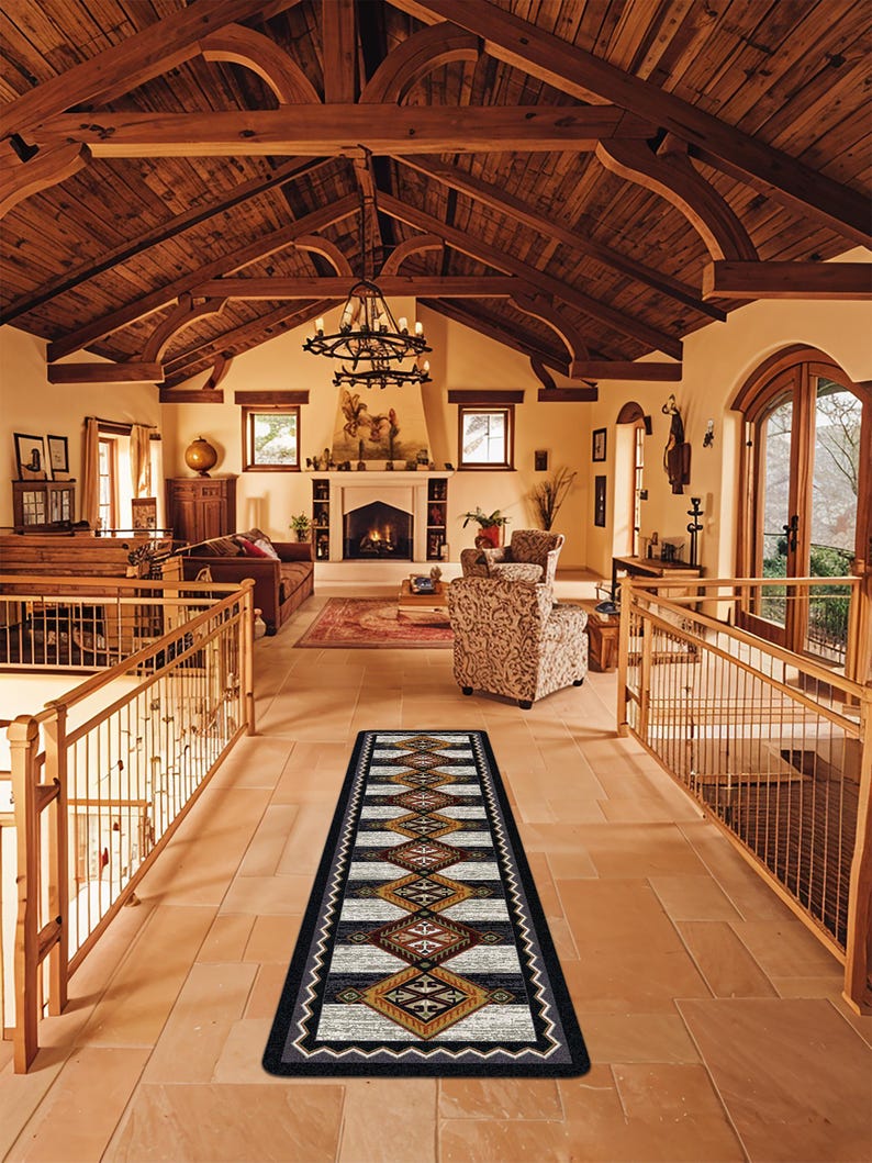 May include: A long, rectangular runner rug featuring a repeating geometric diamond pattern in shades of black, white, tan, and rust orange, bordered by a thick black frame with a white zigzag line detail running along the entire outer edge.