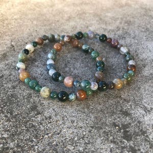 May include: Two bracelets made of green, brown, and white agate beads. The bracelets are stacked on top of each other.