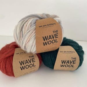 May include: Three balls of yarn in different colours: red, green, and white with pink and grey stripes. Each ball has a brown paper label with the text "we are knitters" and "THE WAVE WOOL".