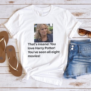 May include: White t-shirt with a picture of a woman and the text "That's insane! You love Harry Potter! You've seen all eight movies!"