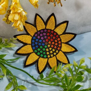 Peut inclure: Un patch brodé de tournesol jaune avec un centre arc-en-ciel. Le tournesol est un symbole populaire d'espoir et de bonheur.