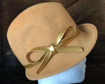 May include: A mustard yellow felt hat with a wide brim and a gold leather bow.