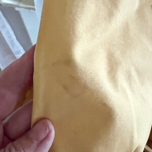 May include: Close-up of a pale yellow fabric with a slightly textured surface.