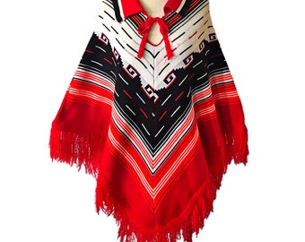May include: Red, white, and black striped knitted poncho with a geometric pattern and fringe trim. The poncho has a collar and a tie at the neck.