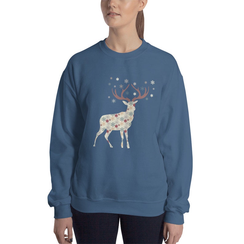 May include: A navy blue sweatshirt with a white silhouette of a deer with snowflake patterned antlers and body. The deer is standing on a white background.