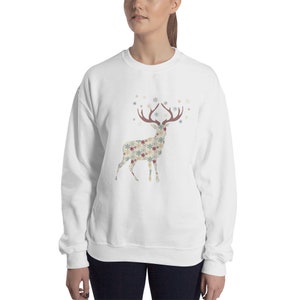 May include: White sweatshirt with a snowflake patterned reindeer design. The reindeer has brown antlers and is surrounded by snowflakes.