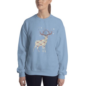 May include: A light blue sweatshirt with a snowflake patterned reindeer graphic. The reindeer has red antlers and is surrounded by snowflakes.