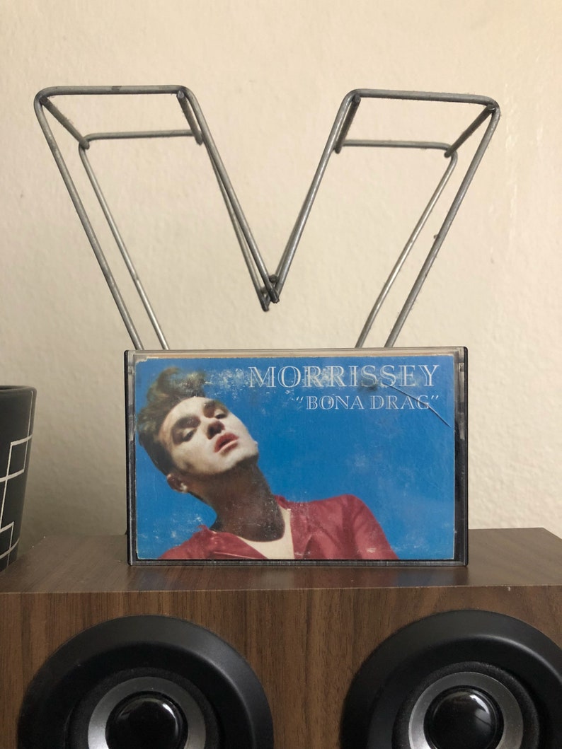 May include: A cassette tape with a blue background and a photo of Morrissey on the front. The cassette tape is titled "Morrissey" and "Bona Drag" in white text.