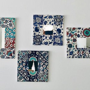 May include: Four decorative mirrors with a white background and blue and red floral patterns. The mirrors are framed with a mosaic of tiles.