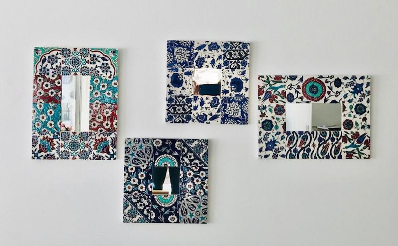 May include: Four decorative mirrors with a white background and blue and red floral patterns. The mirrors are framed with a mosaic of tiles.