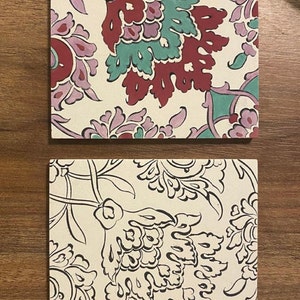 May include: Two square ceramic tiles with a white background and floral patterns. The top tile has a red, pink, and green floral pattern. The bottom tile has a black floral pattern.