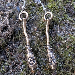 Peut inclure: Une paire de boucles d'oreilles en argent avec un motif de balai. Les balais sont en métal et présentent un design détaillé. Les boucles d'oreilles sont suspendues à des crochets en argent.