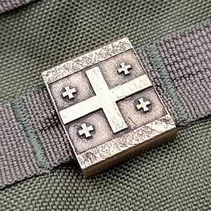 May include: A silver metal pin featuring the flag of Georgia. The flag is a white cross on a red background with four smaller crosses in the corners.