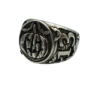 Puede incluir: Un anillo de plata con un dise&ntilde;o detallado de una calabaza de Halloween y murci&eacute;lagos. El anillo es un accesorio de tem&aacute;tica de Halloween.