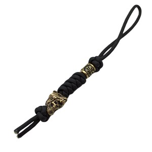 May include: Black paracord keychain with a brass wolf head bead and a brass bead with a circular design.