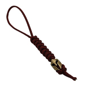 May include: A red and black paracord keychain with a brass Spartan helmet charm.