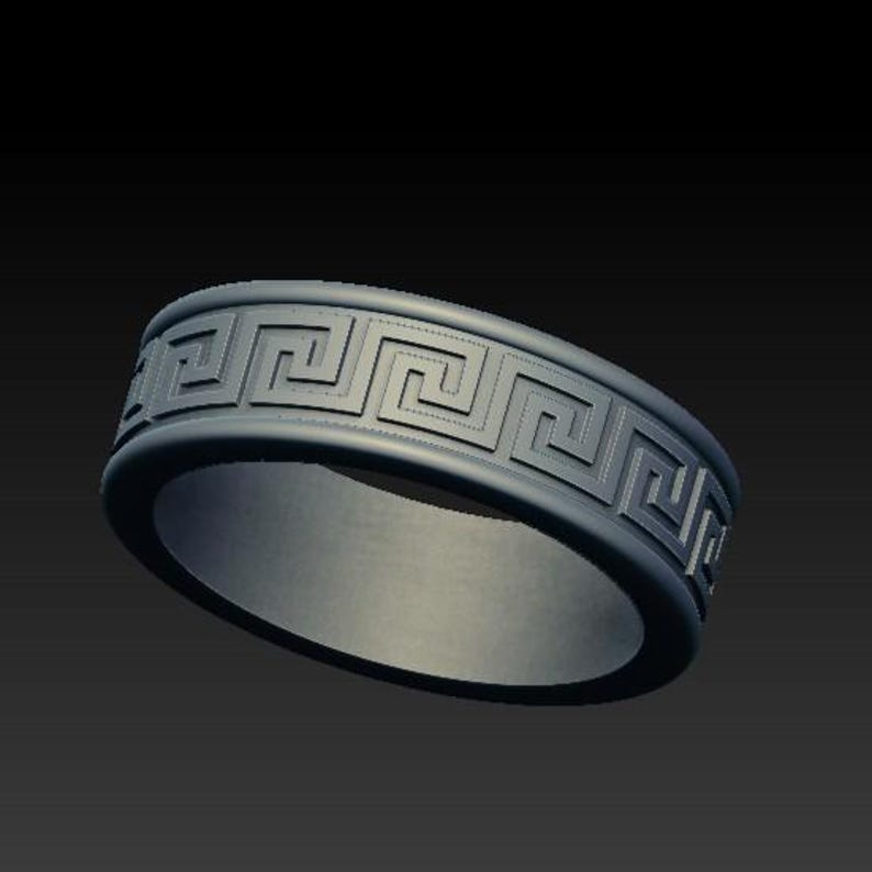 May include: A dark gray band ring featuring a continuous embossed Greek key pattern around the exterior surface. The ring has a smooth interior finish and a matte appearance, showcasing a repeating geometric meander design along the outer edge.
