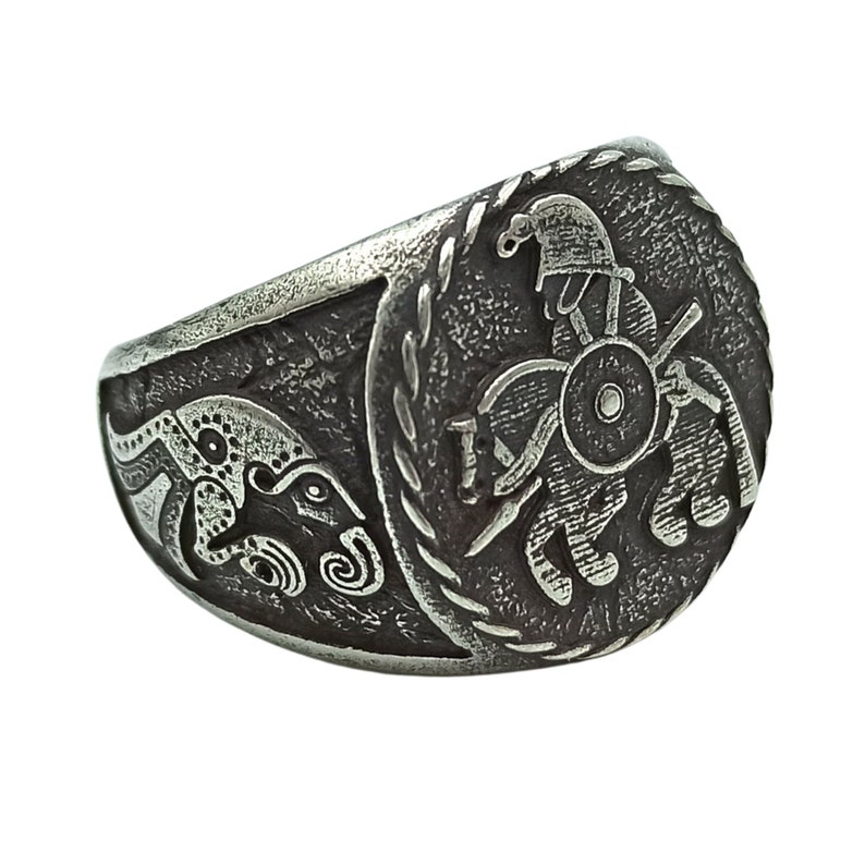 May include: A silver ring with a detailed design of a warrior on horseback. The warrior is wearing a helmet and holding a spear. The ring is set against a white background.