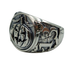 Puede incluir: Un anillo de plata con una talla detallada de una calabaza de Halloween en un lado y el n&uacute;mero "13" en el otro.