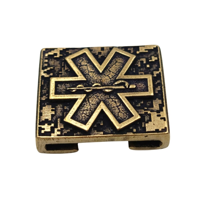 Pode incluir: Um amuleto de metal dourado com um s&iacute;mbolo de estrela da vida preto. O amuleto tem uma superf&iacute;cie texturizada e uma forma quadrada.