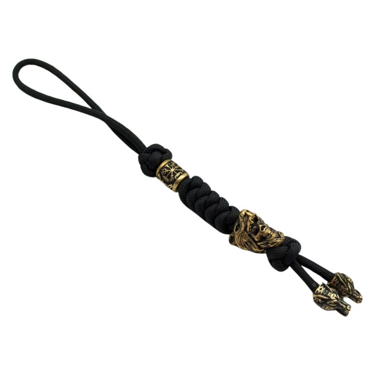 May include: Black paracord keychain with a gold metal bead and two wolf head charms.