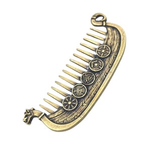 A bronze metal beard comb with a Viking ship Drakkar design. The comb features a ship's hull with decorative shields and a dragon head at the front. The comb's teeth are evenly spaced and extend from the ship's hull.