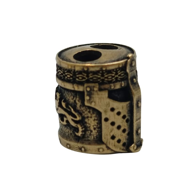 May include: A bronze-colored metal bead shaped like a knight's helmet with a lion design on the side. The helmet has a visor and a decorative band around the top.