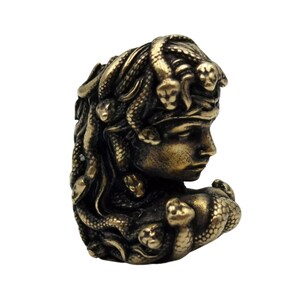 Puede incluir: Una estatua dorada de Medusa, una figura mitol&oacute;gica griega con serpientes por cabello. La estatua es detallada y muestra la cara y el cuello de Medusa, con serpientes envueltas alrededor de su cabeza y hombros.