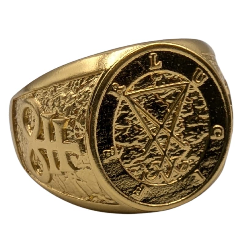 May include: A gold-toned ring featuring a textured surface with a central circular emblem displaying the Sigil of Lucifer. The letters L, U, C, and I are embossed around the perimeter of the circle, and a symbol is engraved on the side of the band.