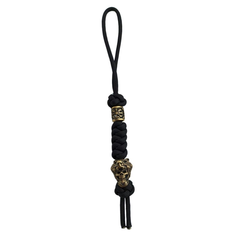May include: Black paracord keychain with a gold skull bead and a gold bead with a decorative design.