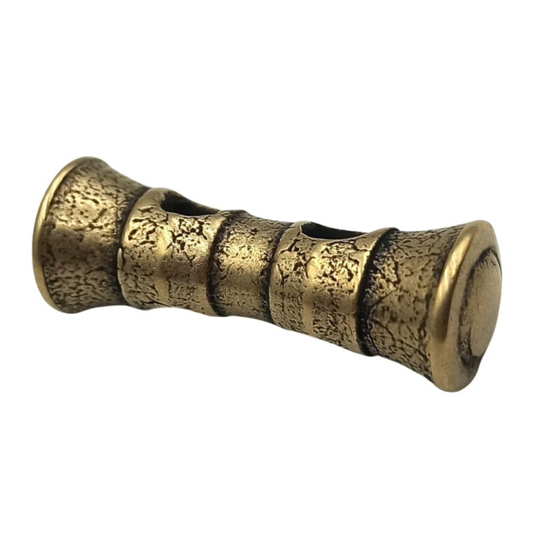 May include: A gold-toned metal whistle with two holes and a textured surface.