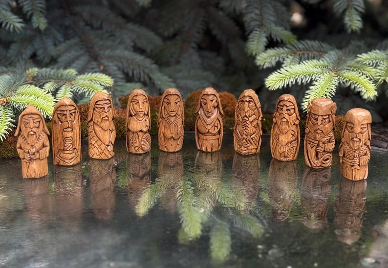 May include: A set of ten small, hand-carved wooden figurines arranged in a row. Each figure features distinct facial expressions, detailed clothing, and carved patterns, with a light brown wood grain finish and a smooth, polished appearance.