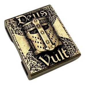 May include: A gold-toned metal charm with a knight's helmet and the words "Deus Vult" in a stylized font.