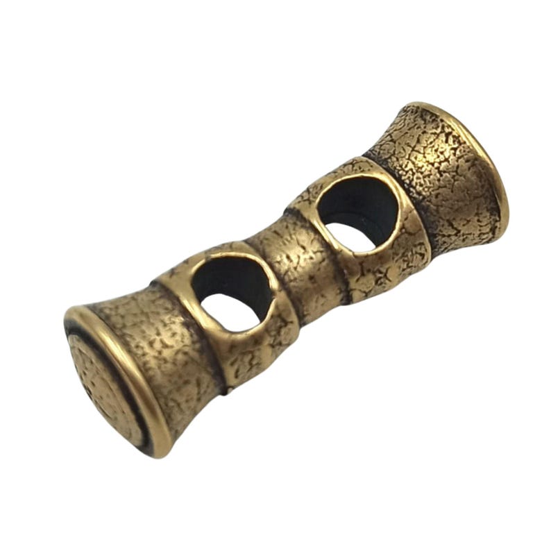 May include: Gold-toned metal bead with a textured surface and three open circles. The bead is designed to be used as a spacer or charm on a bracelet or necklace.