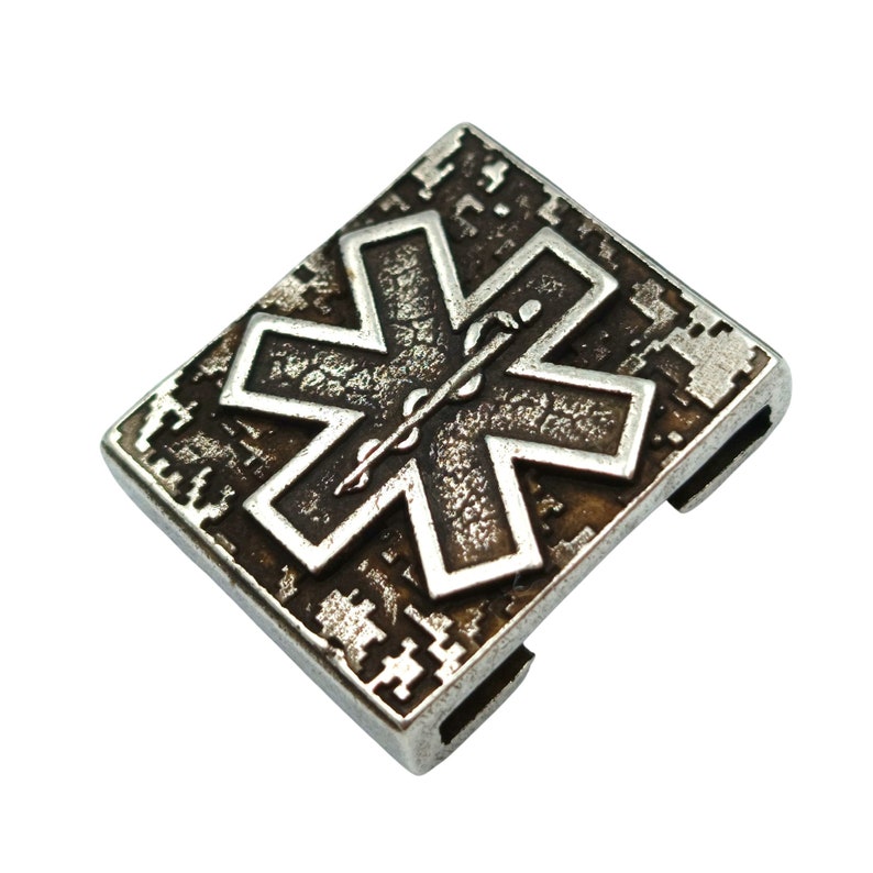 Pode incluir: Um amuleto de metal prateado com um s&iacute;mbolo de estrela da vida preto e branco. O amuleto tem um fundo texturizado e um recorte na parte de tr&aacute;s para prender a uma pulseira ou colar.