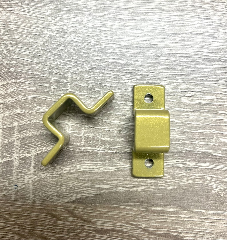 May include: Two gold metal brackets, one with a curved shape and the other with a rectangular shape. Both brackets have holes for mounting.