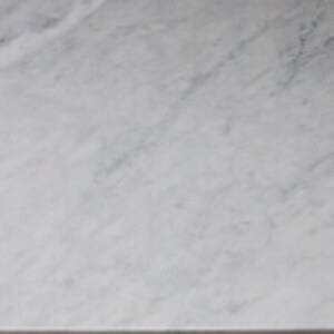 May include: A close-up of a smooth, white marble surface with subtle gray veining.