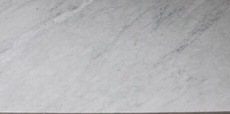 May include: A close-up of a smooth, white marble surface with subtle gray veining.