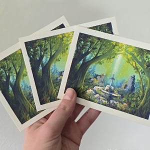 Könnte beinhalten: Ein Satz von vier quadratischen Kunstdrucken mit einem Fantasy-Landschaftsgemälde. Das Kunstwerk zeigt eine Waldszene mit einer Steinstruktur und einem Schwert, das von Sonnenlicht durchflutet wird. Die Drucke haben einen weißen Rand.
