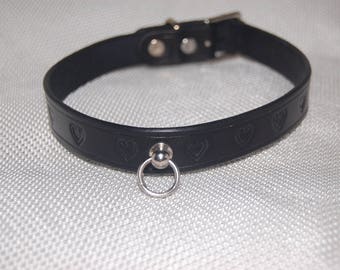 Könnte beinhalten: Ein schwarzes Lederhalsband mit einem silbernen Ring und herzförmigen Ausschnitten.